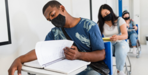 Students wearing mask study in a high school classroom.