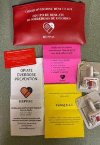 The contents of a Naloxone prevention supply bag from a community based organization are displayed on a table. 